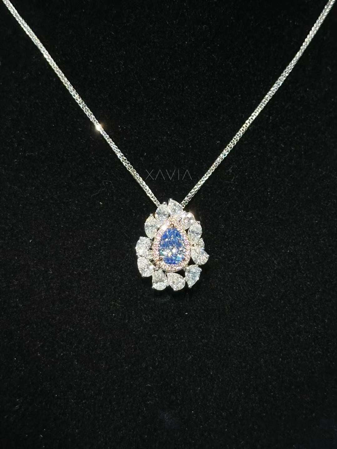 Pear cut blue diamond floral halo pendant necklace with marquise diamond cluster and platinum chain on black background