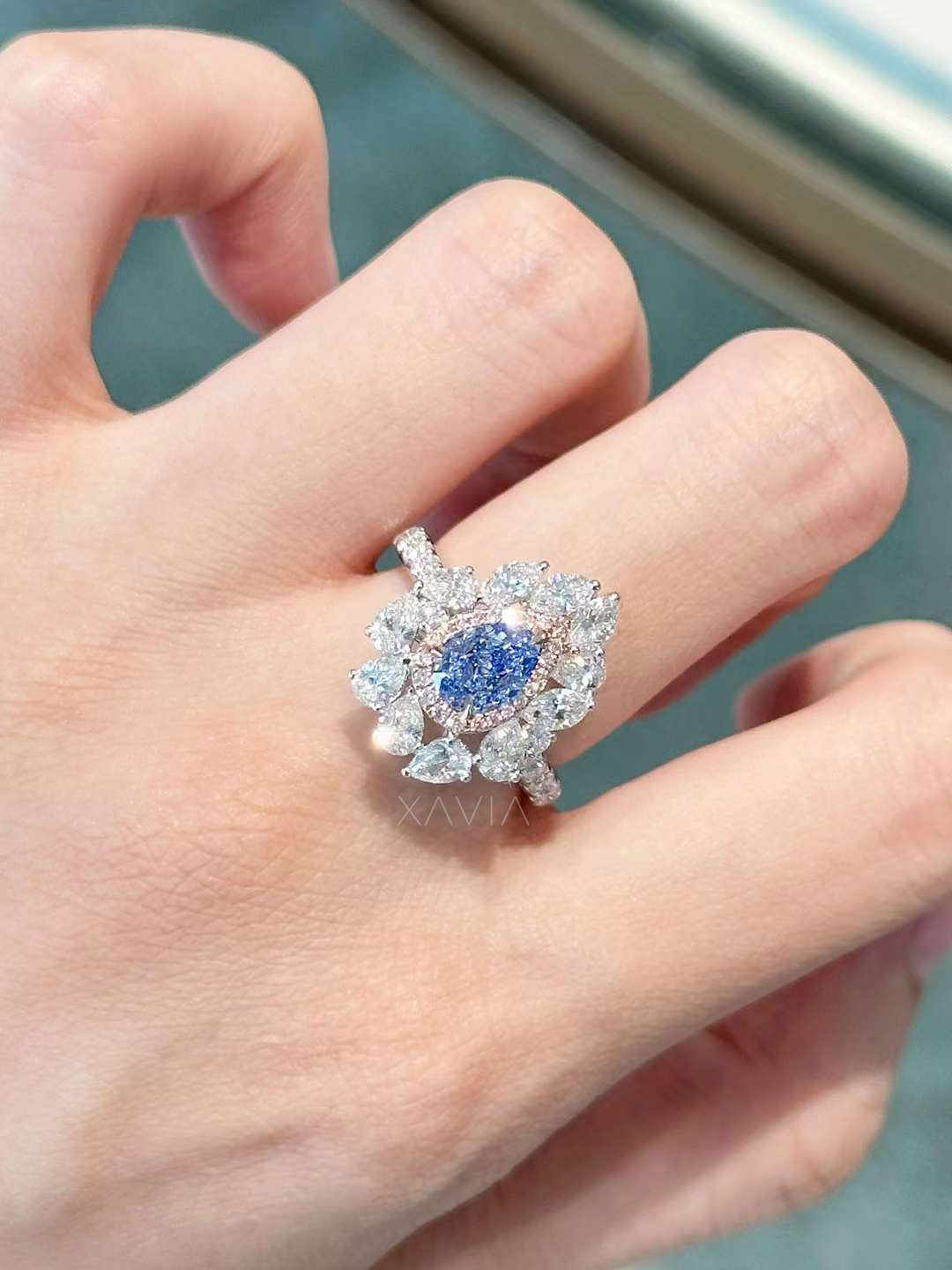 Luxury pear cut blue lab diamond halo ring with floral marquise cluster, pavé shank, worn on finger