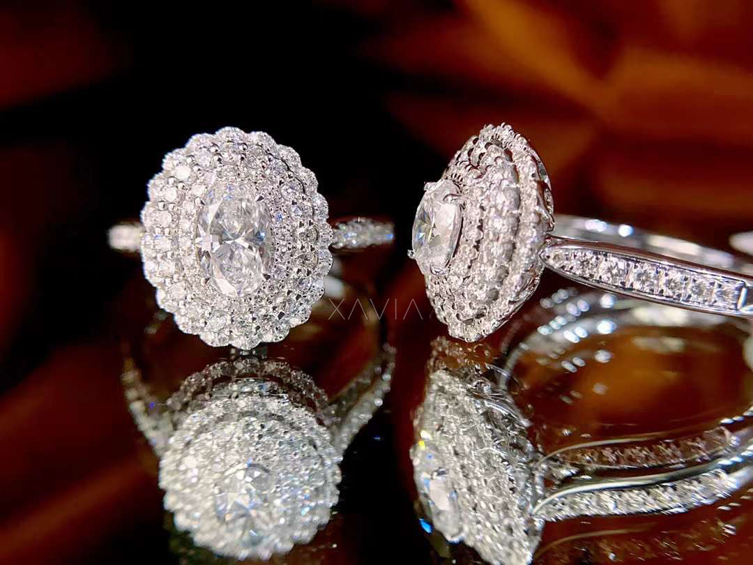 Close-up of a diamond ring and earrings on a reflective surface with a blurred background