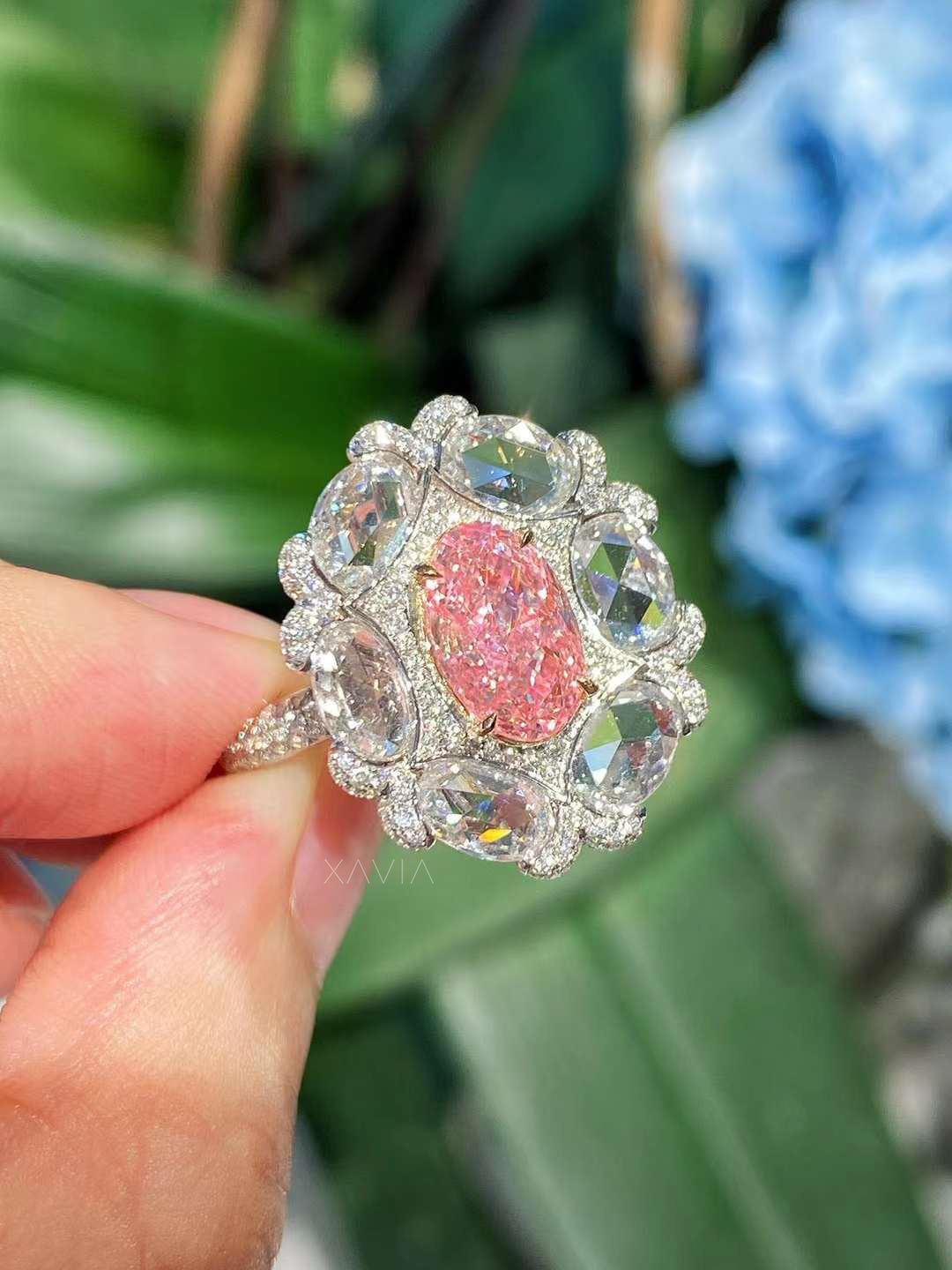 angled side profile showing rose-cut floral halo diamonds surrounding fancy pink oval diamond centerpiece in luxury ring