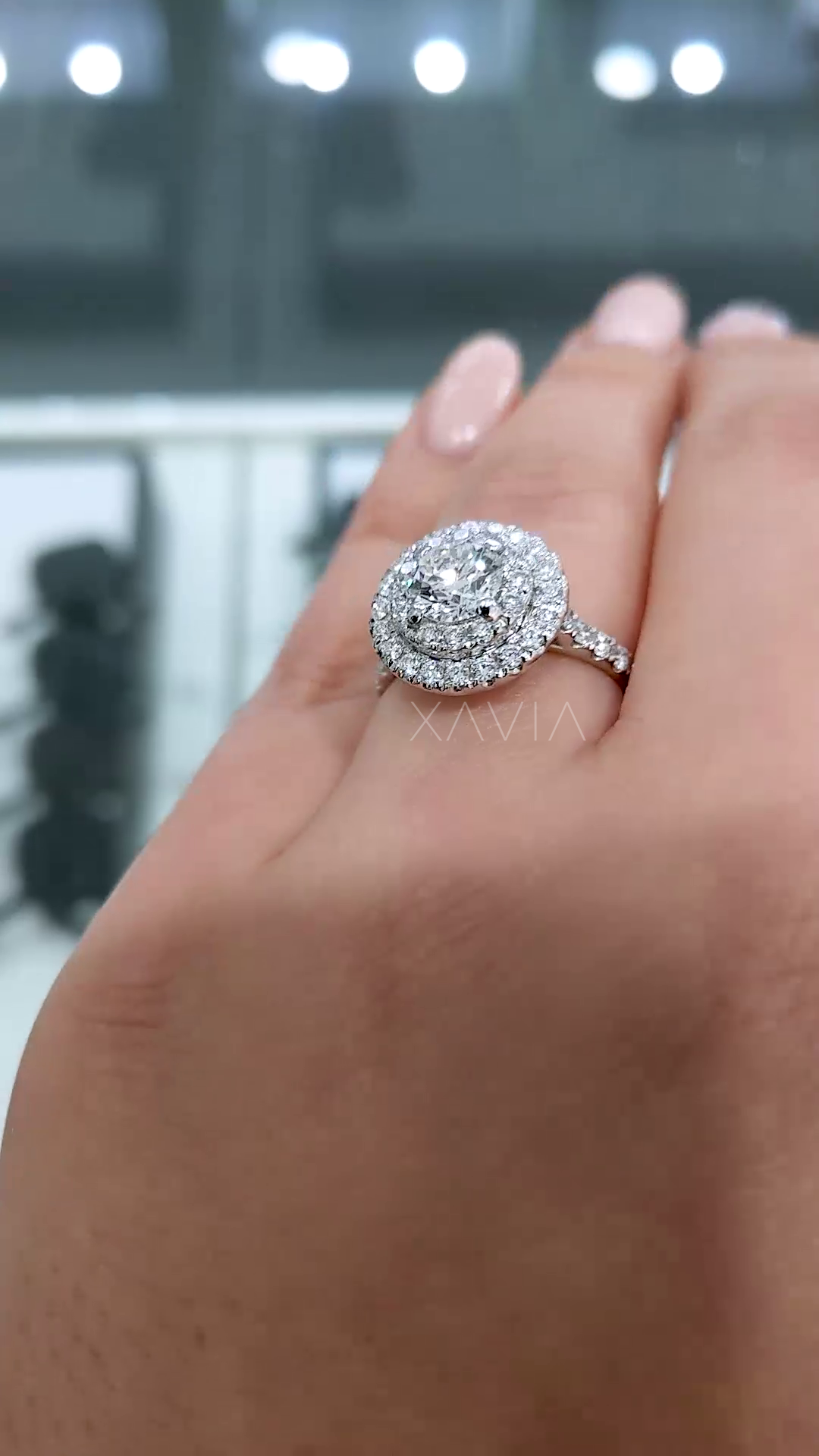 angled close-up of round diamond engagement ring featuring layered double halo pavé design and slim diamond band with intense sparkle reflections