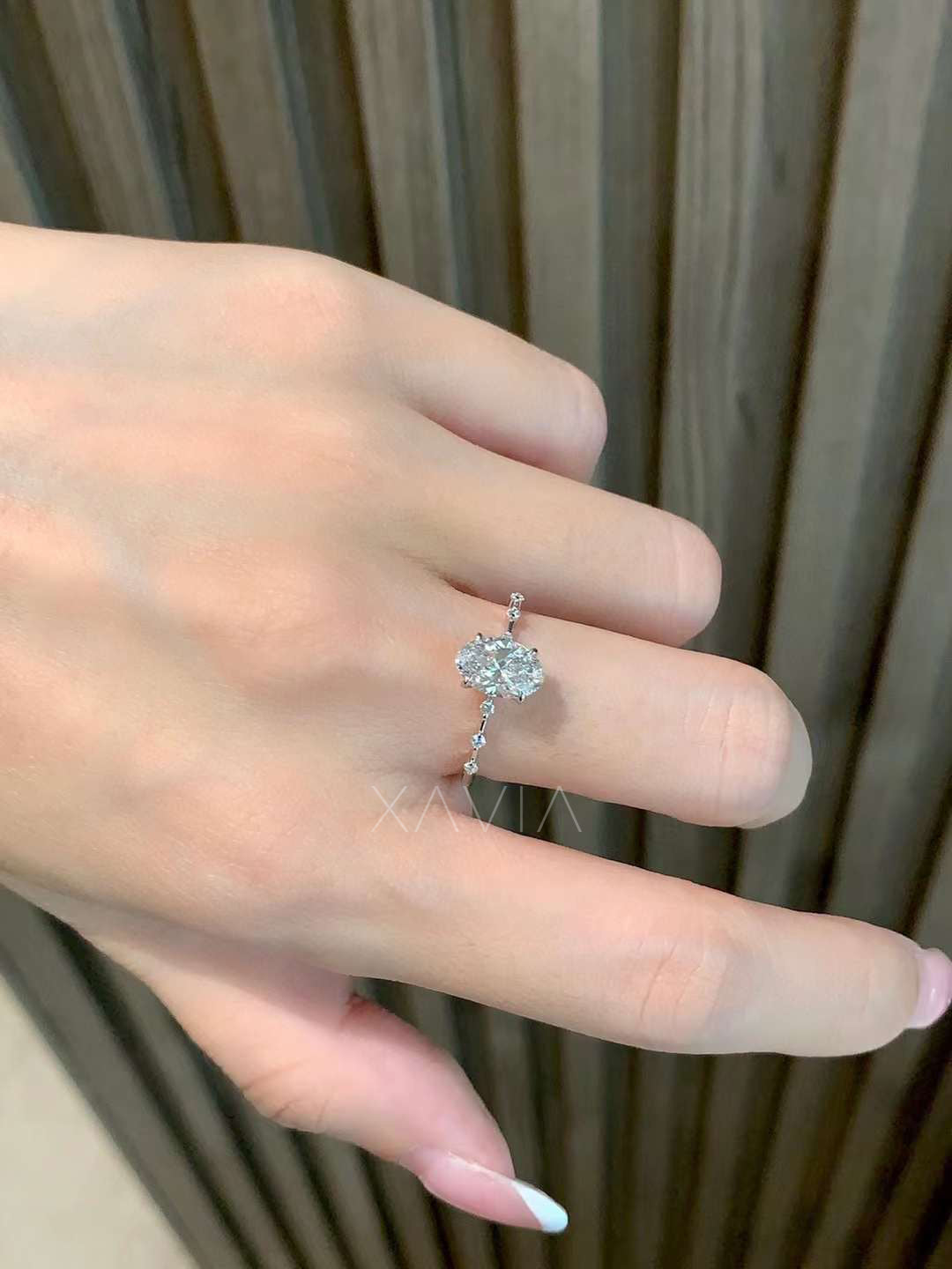 angled side view of oval cut lab diamond solitaire ring with round beaded side stones in fine setting