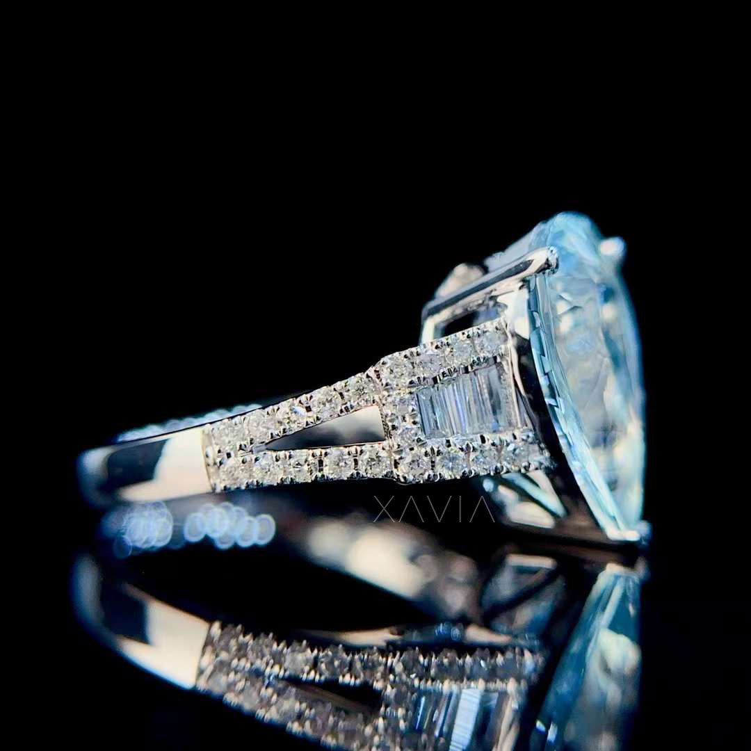 Angled side shot of pear cut aquamarine ring highlighting architectural split shank band and baguette diamond halo detailing