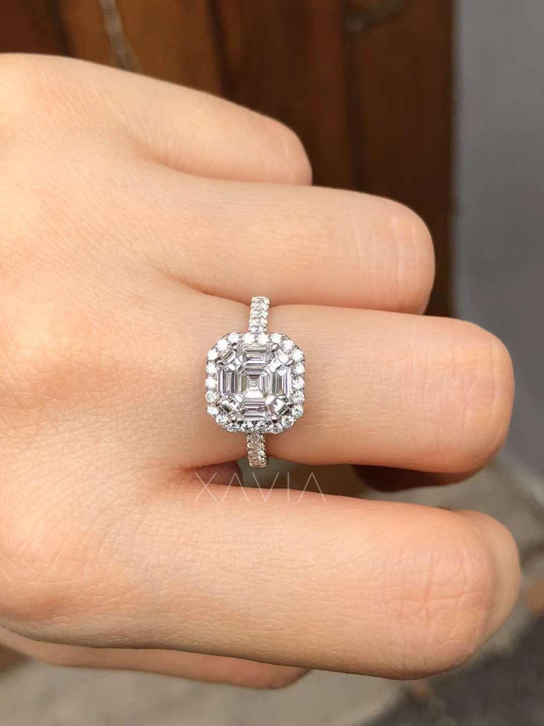 top view of asscher cut halo diamond ring worn on hand highlighting geometric baguette halo and round diamond frame brilliance