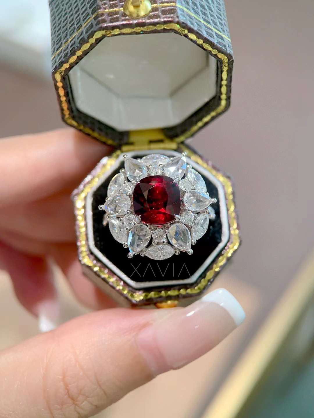 close-up of Astrielle ruby cocktail ring featuring cushion ruby center and pear marquise diamond floral halo in platinum setting