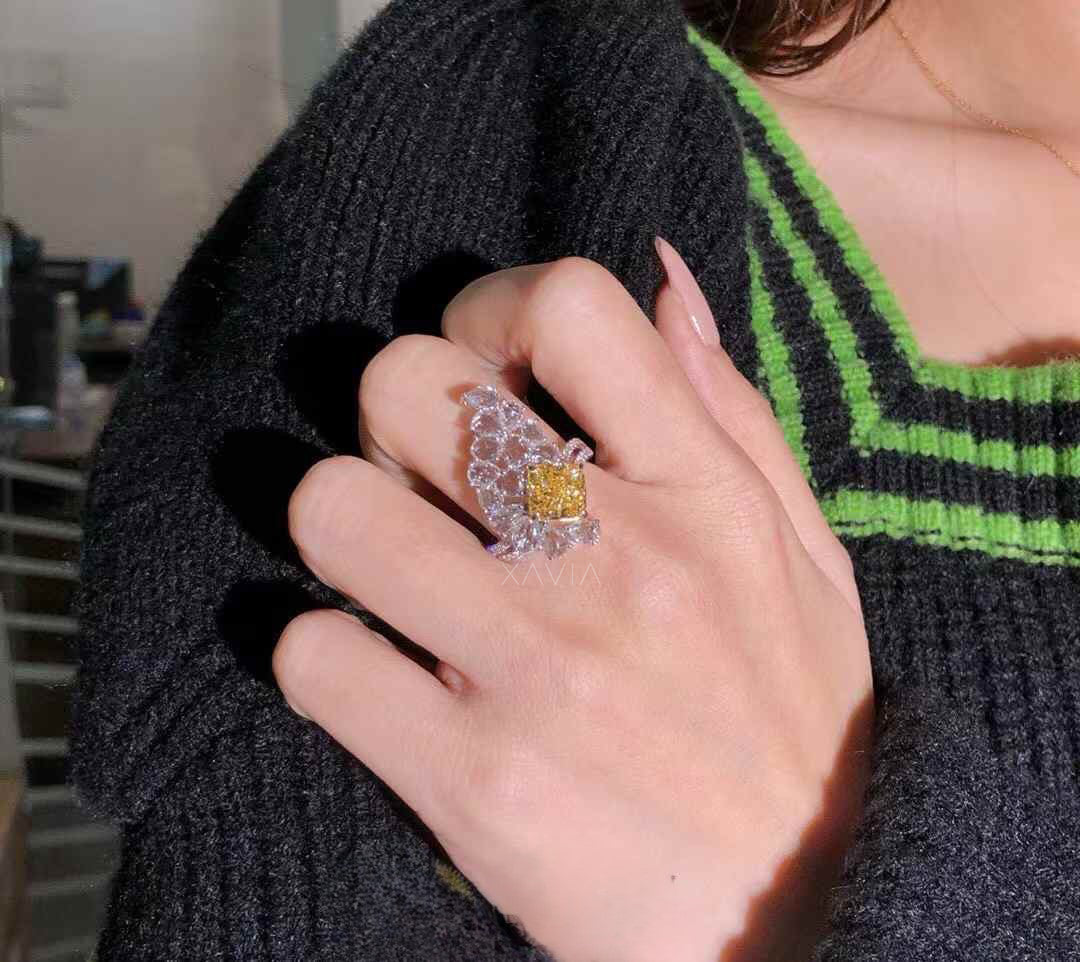 Angled view of dramatic asymmetrical floral cluster diamond ring showcasing yellow cushion cut center stone with marquise and pear halo diamonds