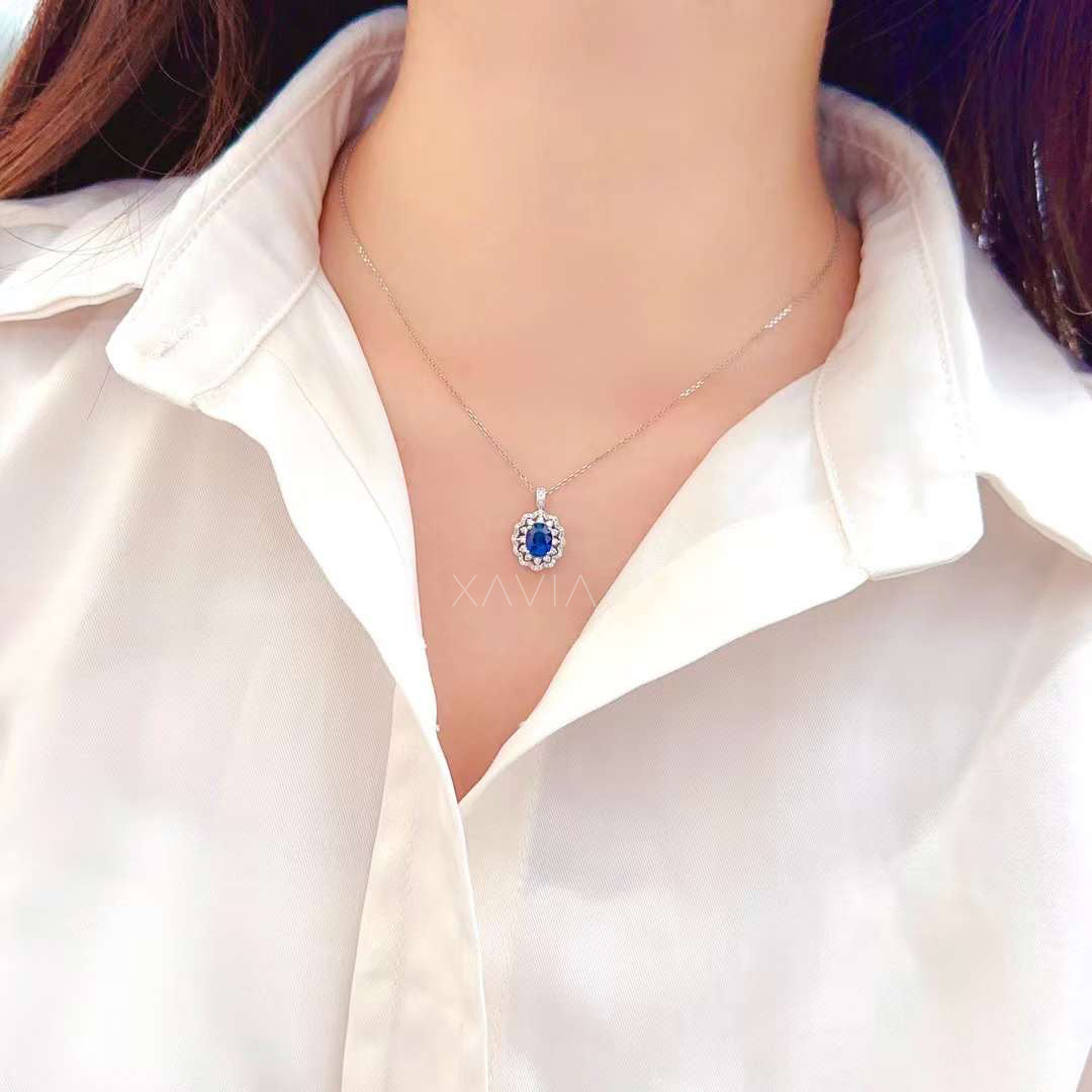 oval blue sapphire halo pendant necklace worn on model featuring floral diamond cluster halo and delicate chain showcasing elegant luxury jewelry styling