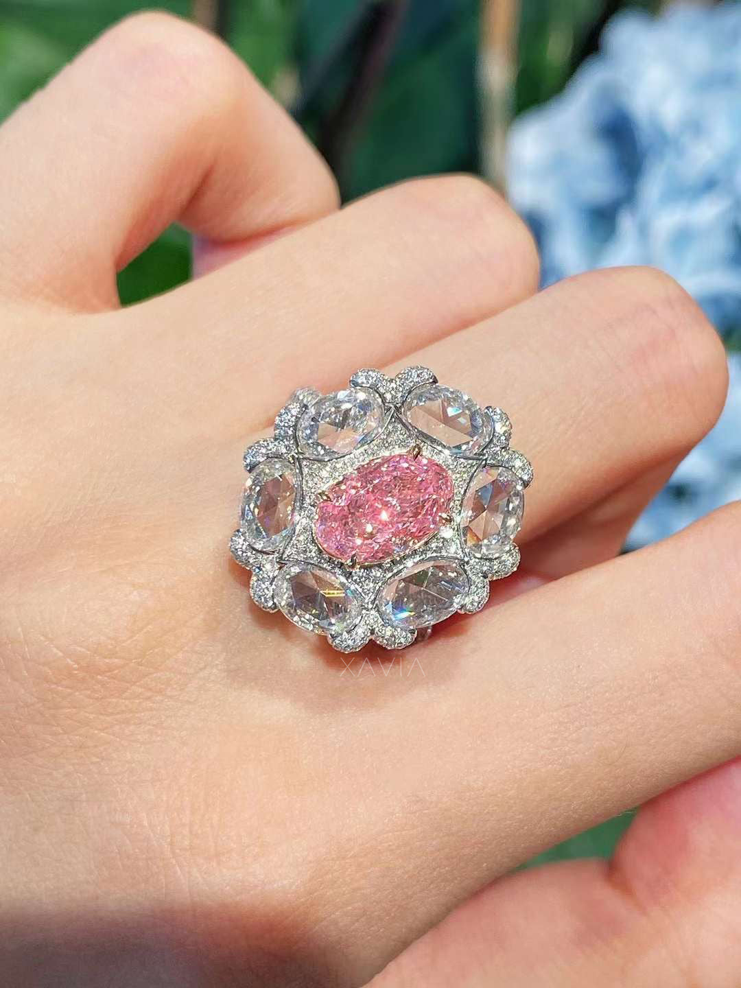 statement pink oval diamond cocktail ring with rose-cut halo shown worn on model’s hand in natural daylight