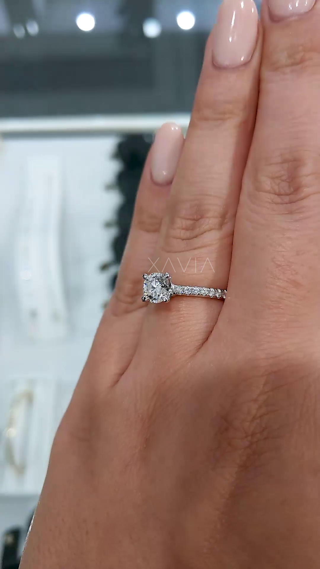 close angle of round brilliant diamond solitaire ring highlighting center stone brilliance, pavé band sparkle and refined luxury finish