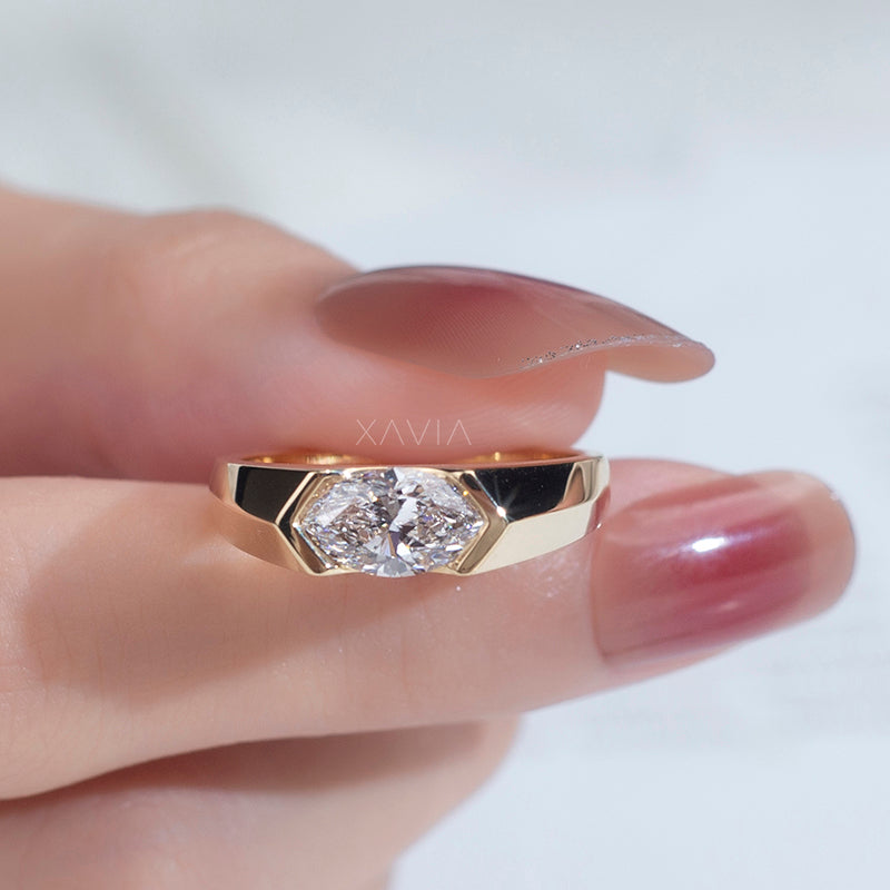 close-up of marquise cut lab-grown diamond ring in yellow gold bezel setting held by model hand with brilliant sparkle