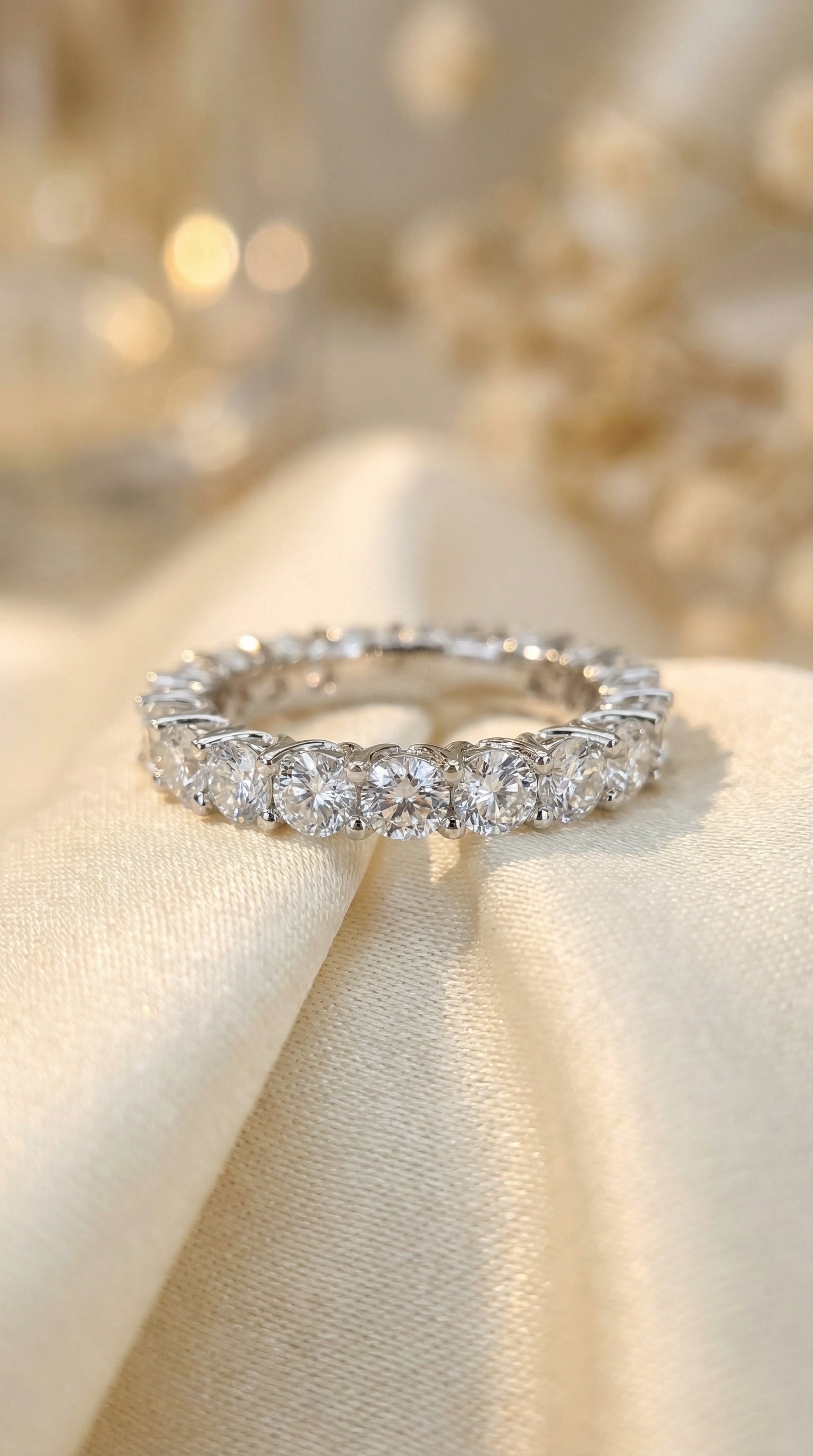close up luxury photography of round brilliant lab diamond eternity band resting on silk fabric showing crown prong setting and diamond fire