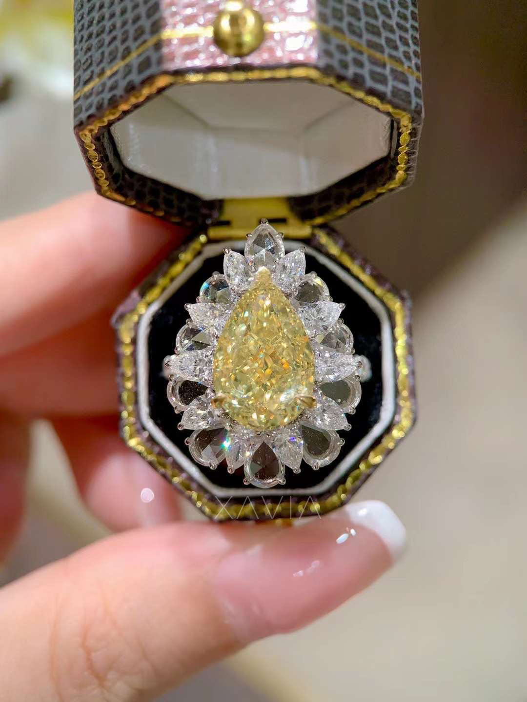 close-up top angle of large fancy yellow pear cut diamond surrounded by marquise halo diamonds in platinum cocktail ring