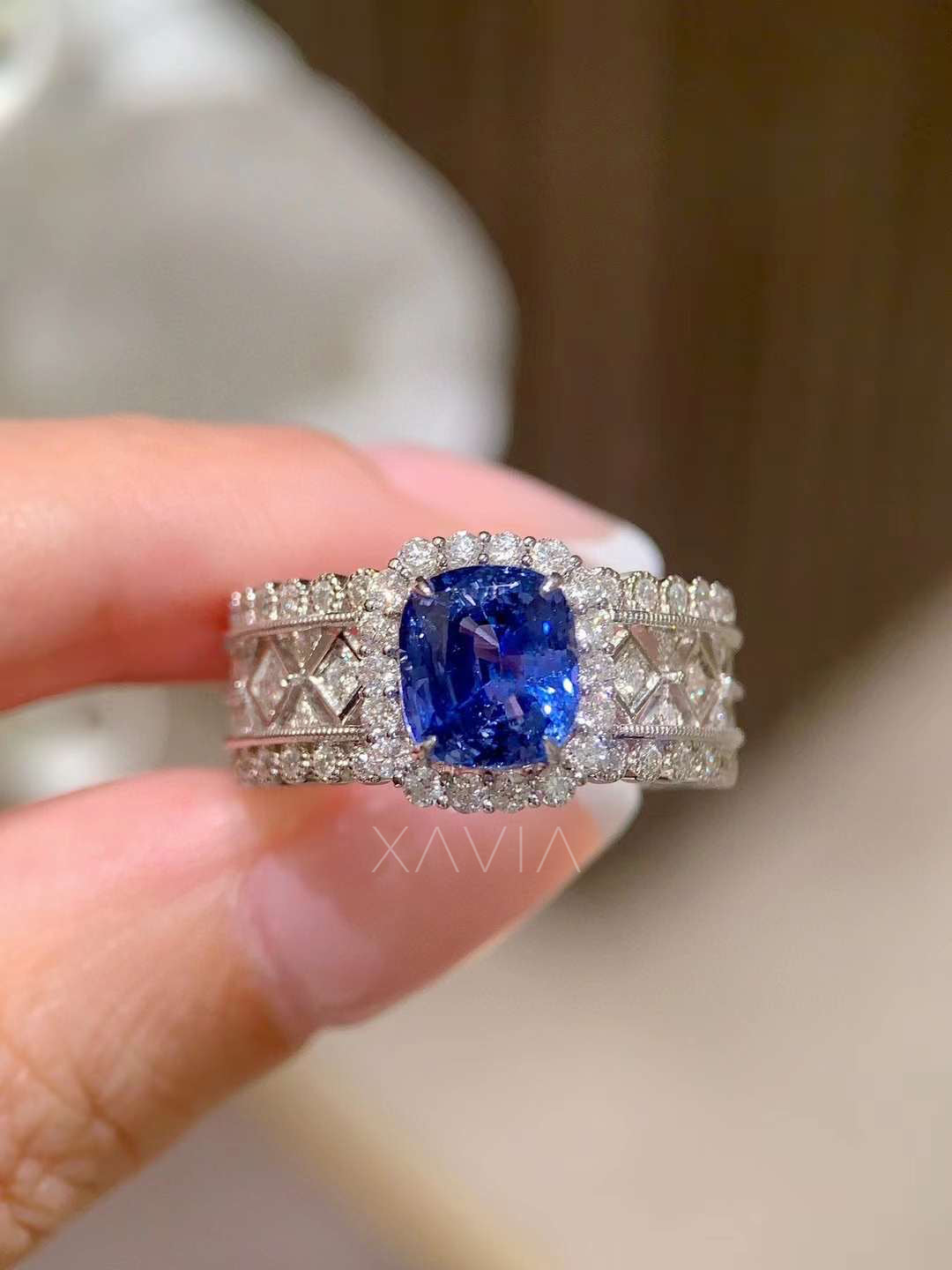 close front view of cushion cut deep blue sapphire halo ring with wide vintage diamond lattice band and pavé diamonds in white gold luxury setting