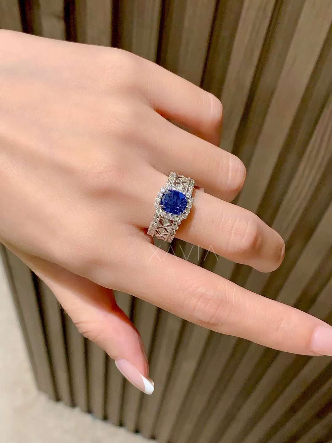 luxury cushion blue sapphire halo ring worn on hand highlighting wide diamond lattice band design and brilliant pavé sparkle