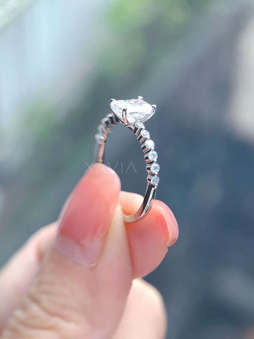 Angled view of cushion cut lab grown diamond solitaire ring with pavé diamond band and refined four prong engagement ring setting