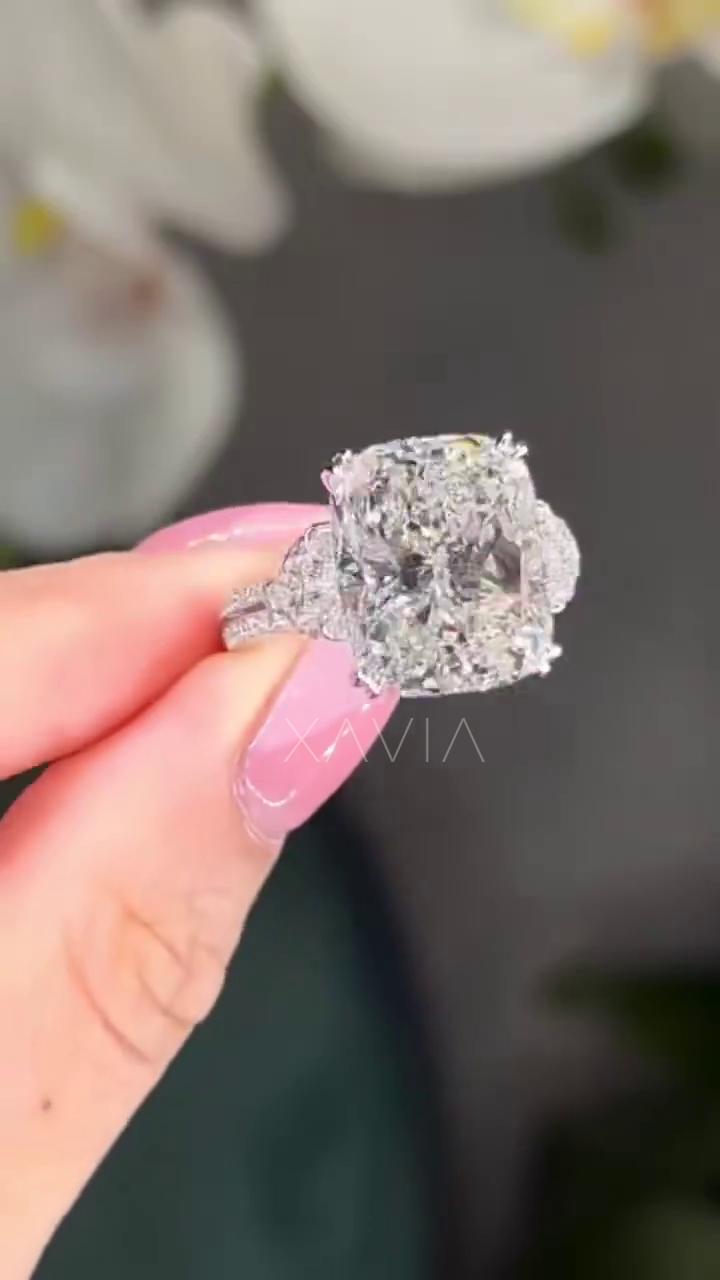 cushion cut three stone lab diamond engagement ring with trapezoid side stones and pavé platinum band worn on model’s hand