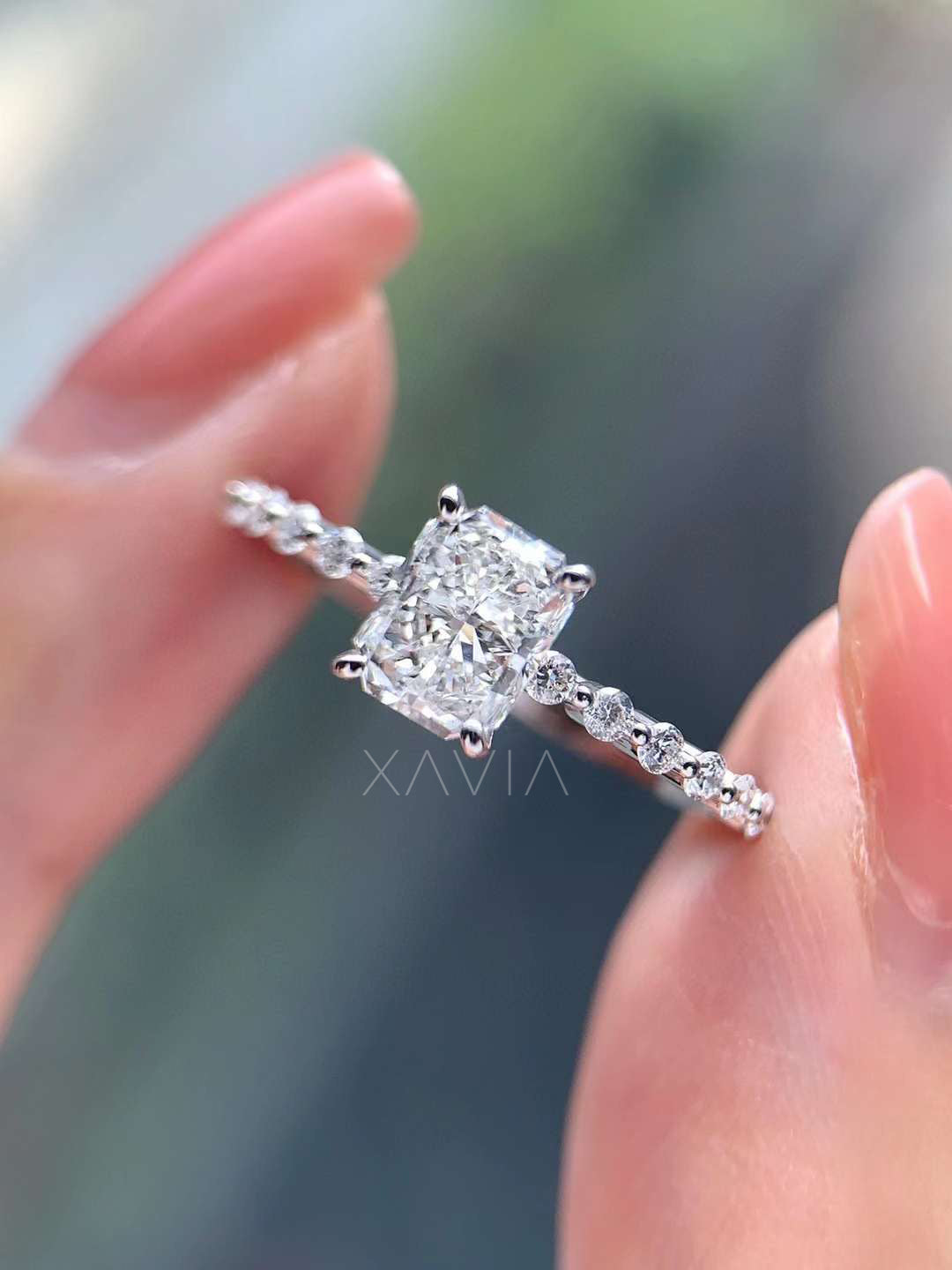 Detailed macro photograph of cushion cut lab diamond solitaire engagement ring with delicate pavé diamonds along thin band