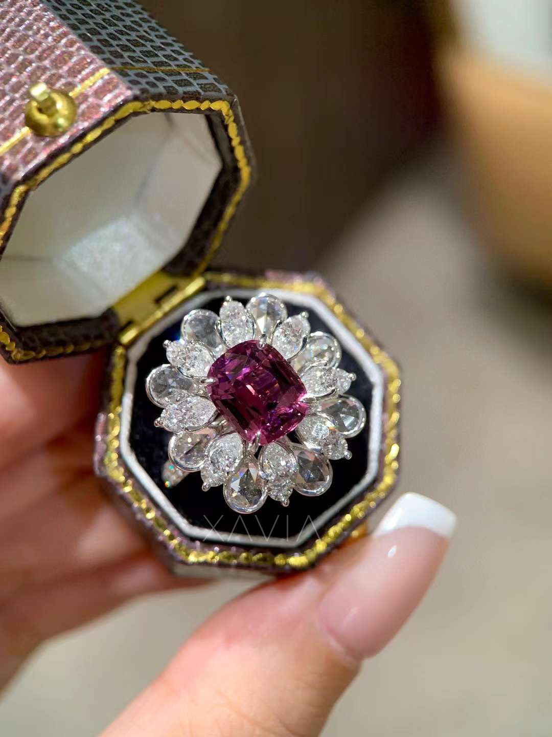 Angled view of statement cocktail ring with vivid pink cushion diamond center and pear shaped diamond floral halo creating radiant petal inspired sparkle
