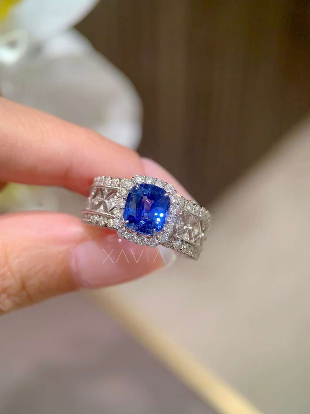 macro close-up of vivid cushion blue sapphire surrounded by round brilliant diamond halo and wide vintage lattice pavé diamond band
