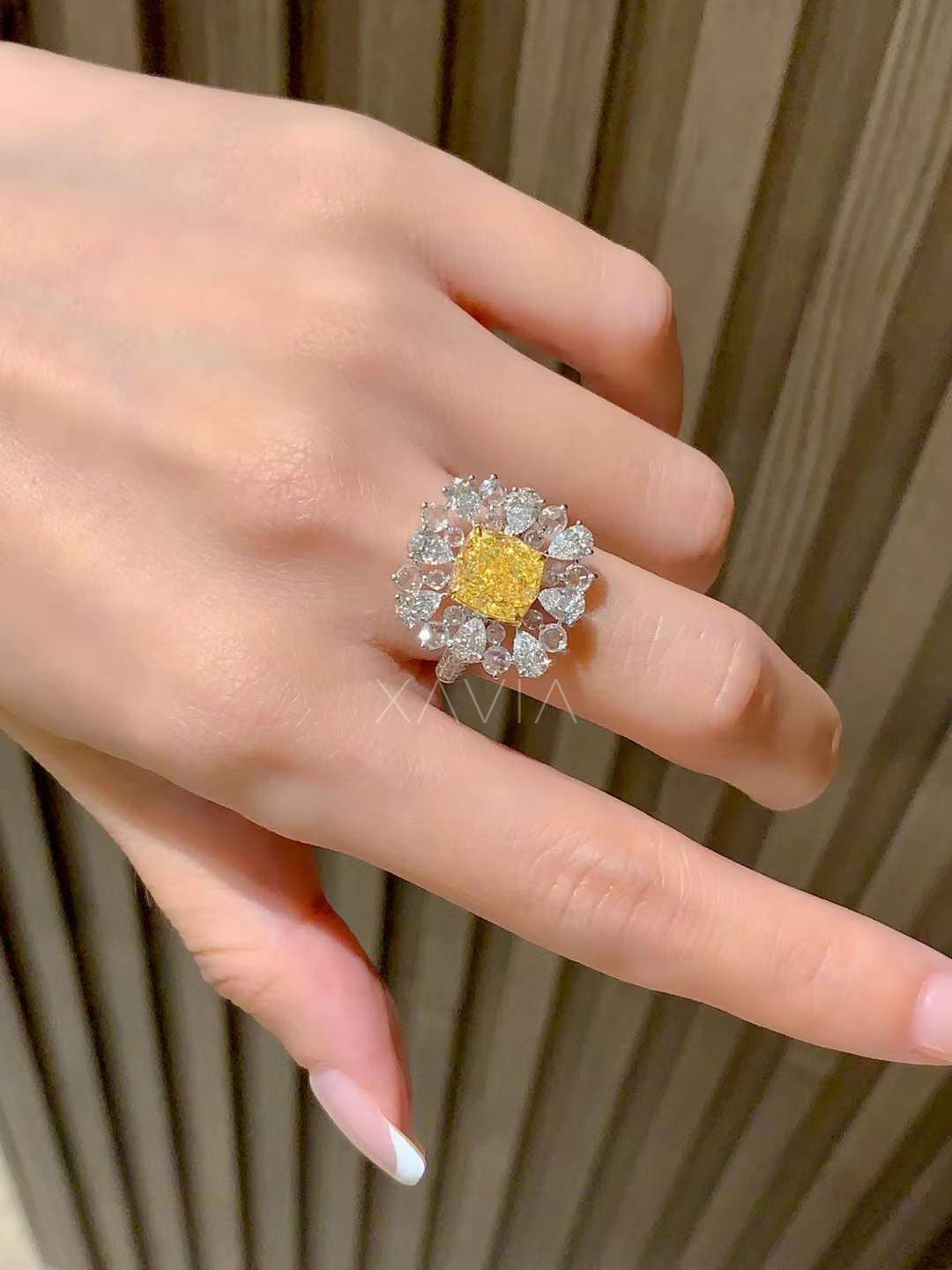 close-up view of cushion fancy yellow diamond cocktail ring with pear-shaped white diamond halo displayed inside luxury jewelry presentation box