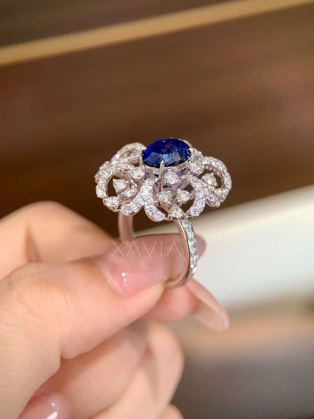 Side profile of elevated oval blue center stone ring showing open gallery floral halo and hand-set lab diamonds