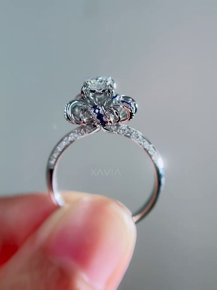 Side angle of luxury engagement ring with pavé diamond band and sapphire petal halo surrounding round brilliant center diamond