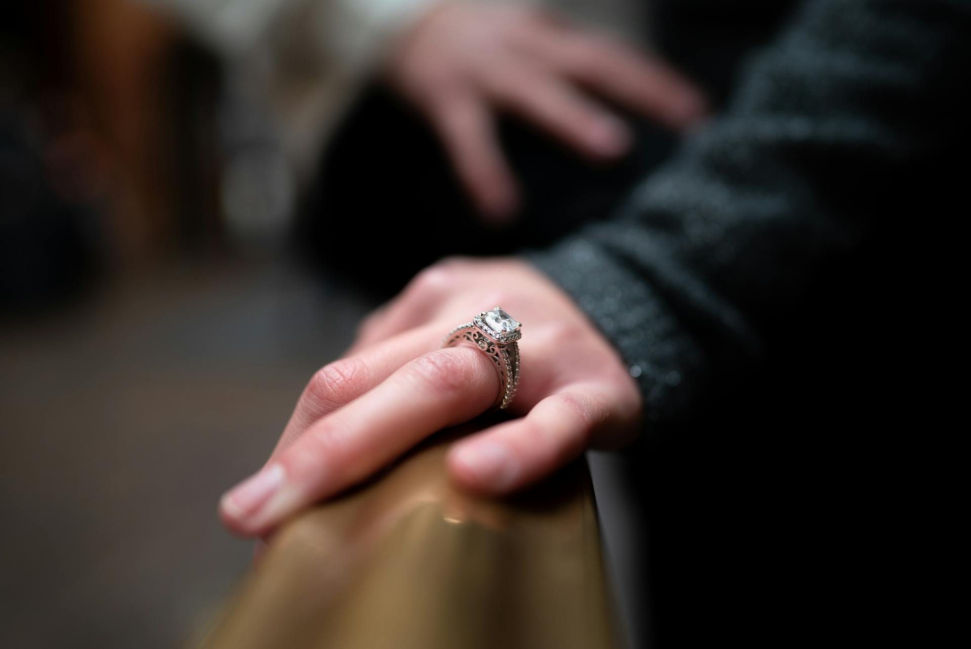 Close-up of a hand wearing a diamond ring with a blurred background - Xavia Jewels
