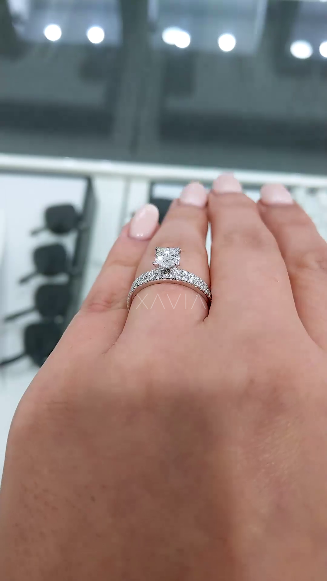 perspective view of round brilliant diamond solitaire ring worn on hand highlighting center stone prominence and delicate pavé band