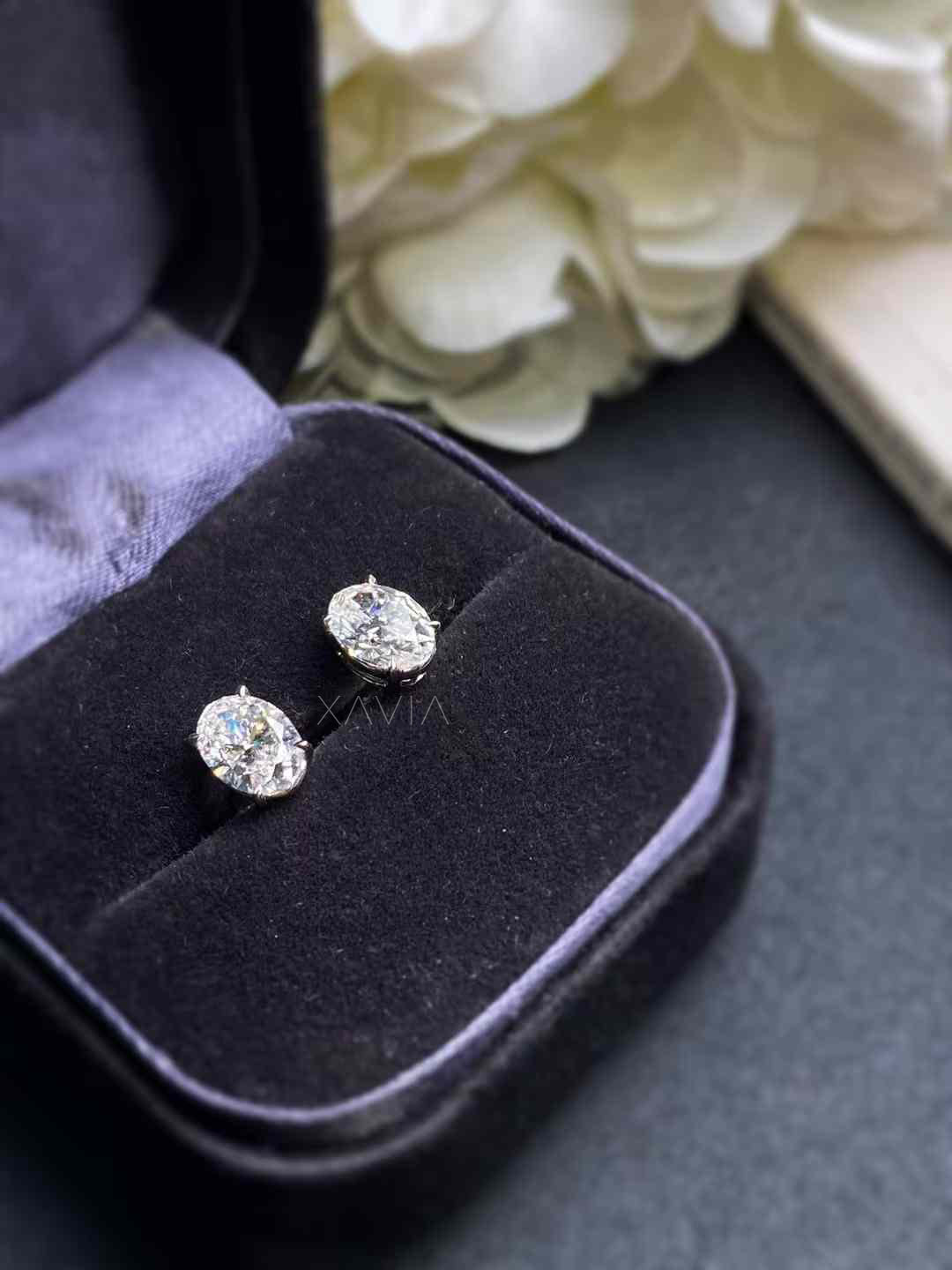 Oval diamond stud earrings displayed in black velvet box