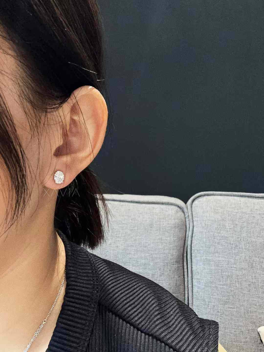 Oval solitaire diamond studs worn on ear, showing size and fit