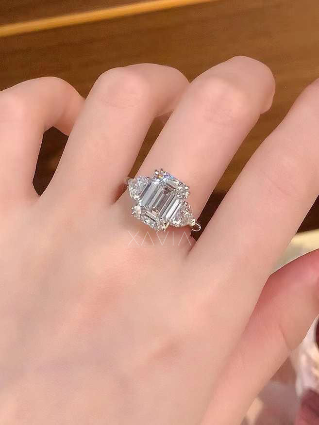 emerald cut lab grown diamond three stone engagement ring worn on hand showing proportion of emerald center stone and trillion side diamonds