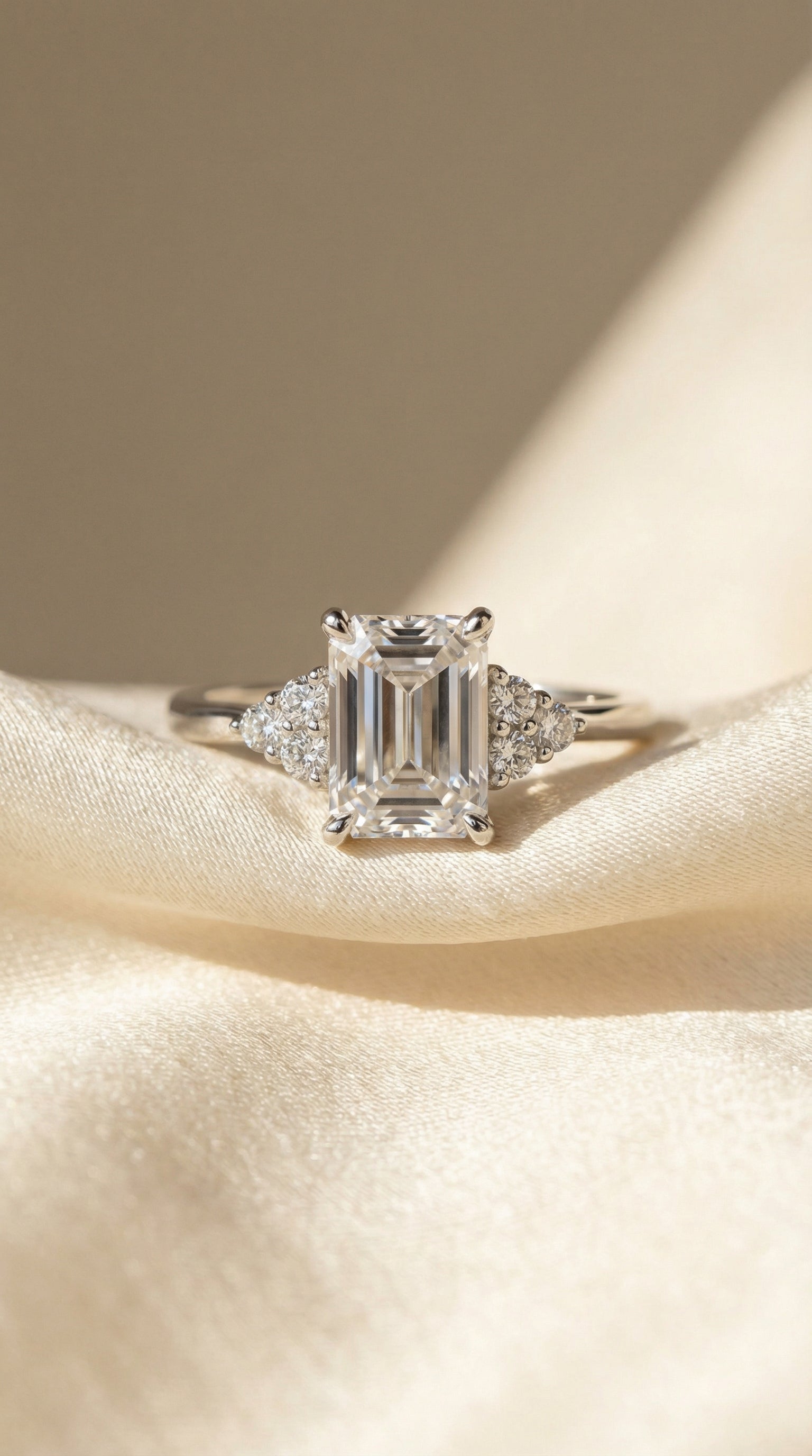 Top view of emerald cut lab diamond engagement ring with symmetrical round diamond cluster side stones and refined polished white gold band