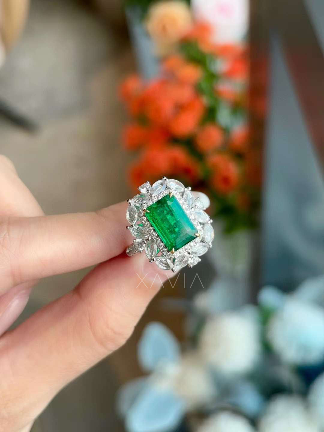 Angled perspective of luxury emerald cut green gemstone statement ring featuring marquise diamond petal halo and pavé frame in white gold setting