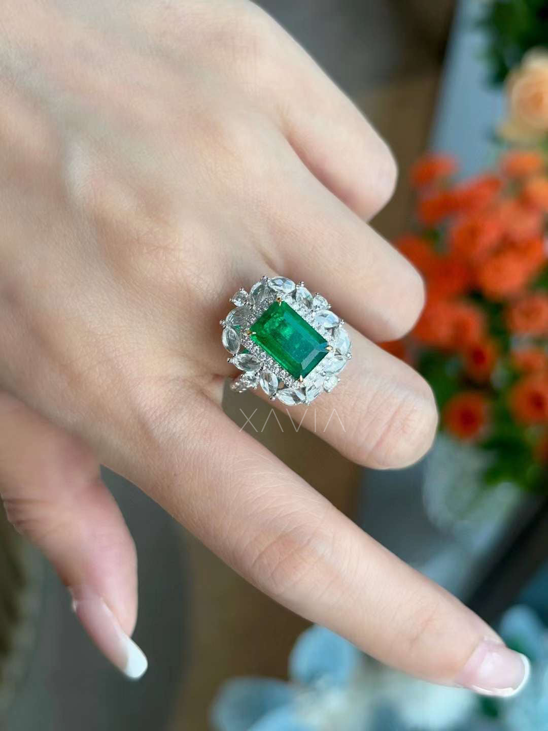 Emerald cut green gemstone statement ring worn on hand showing dramatic marquise diamond floral halo and pavé halo sparkle in elegant cocktail design