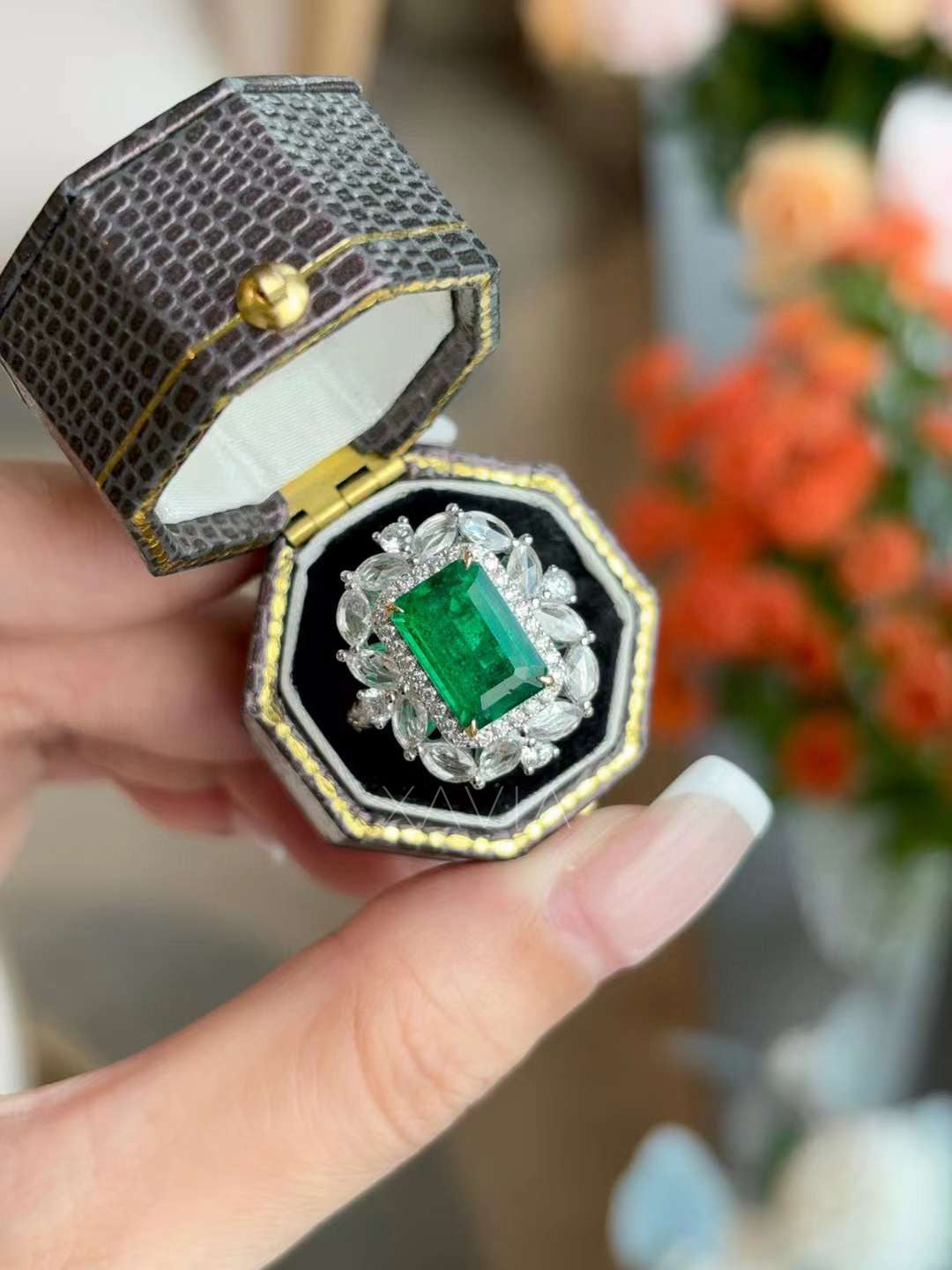 Emerald cut green gemstone halo ring displayed inside luxury ring box highlighting marquise and round diamond floral cluster halo and pavé halo frame