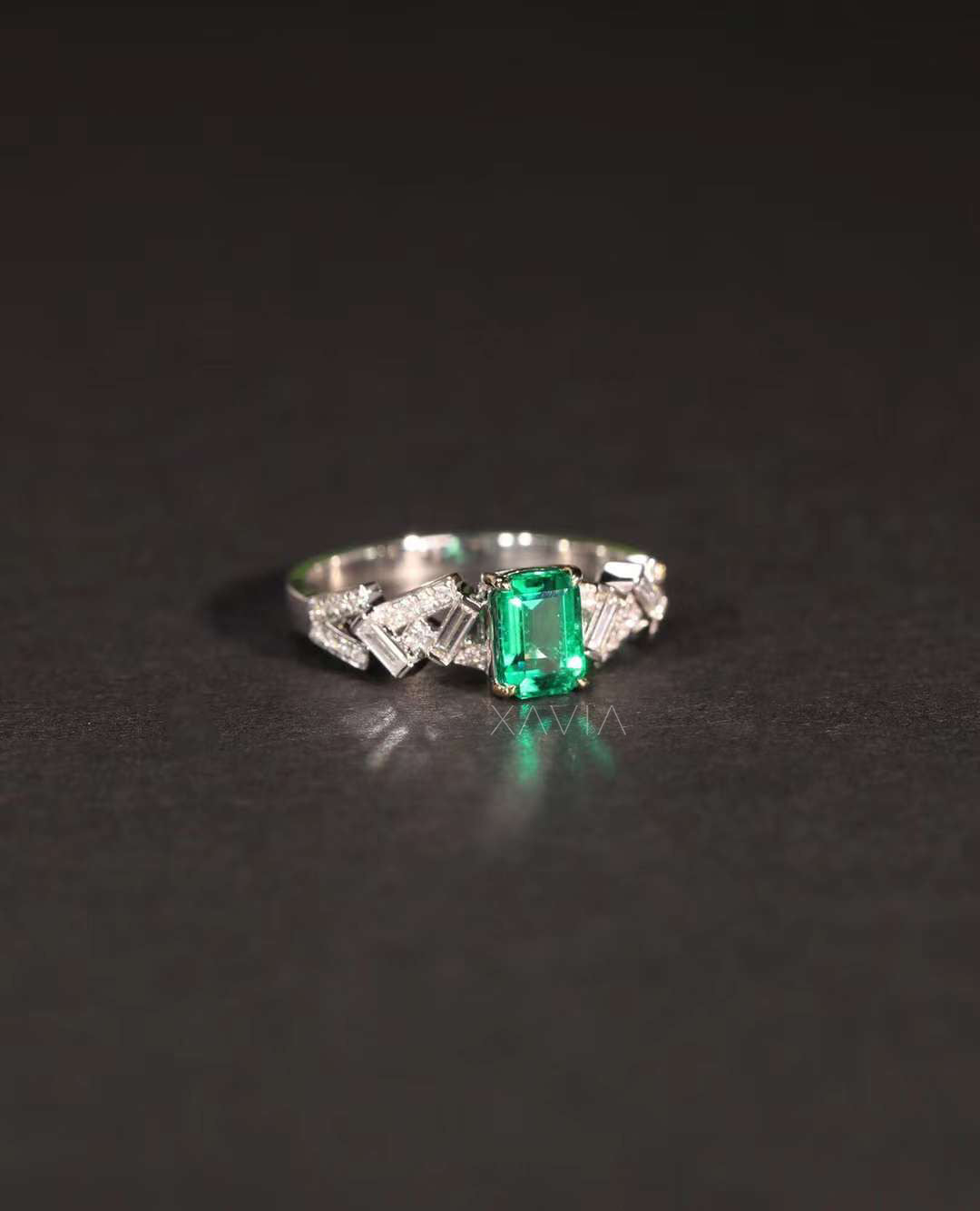 Front view of emerald cut green center stone engagement ring with symmetrical geometric lab diamond side detailing