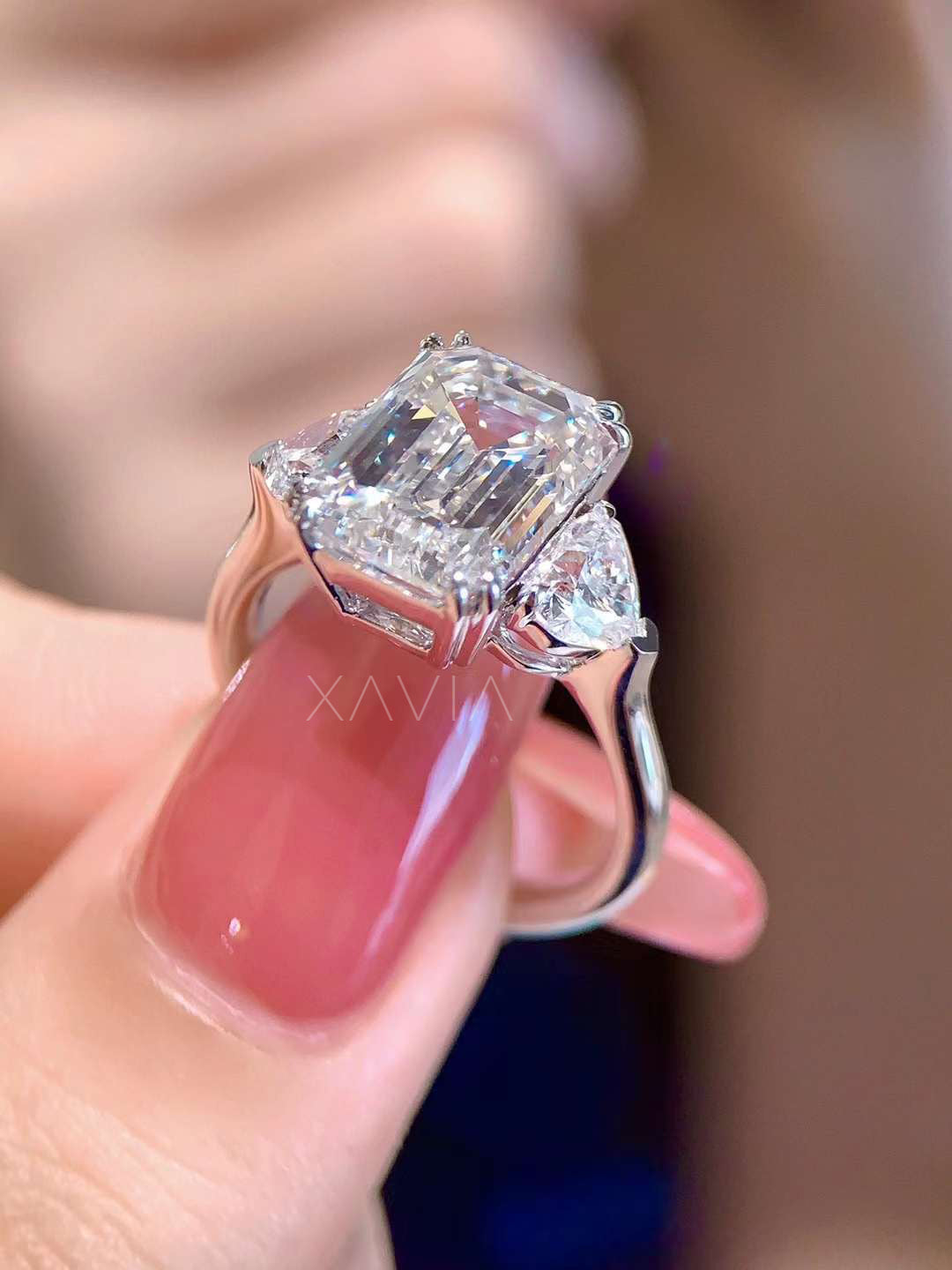 side profile of emerald cut lab grown diamond engagement ring showing elevated basket setting and trillion cut side diamonds on polished band