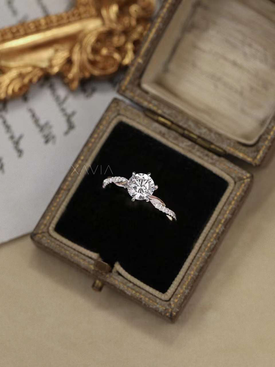 Luxury flatlay of round diamond solitaire engagement ring with pavé twisted band in antique box