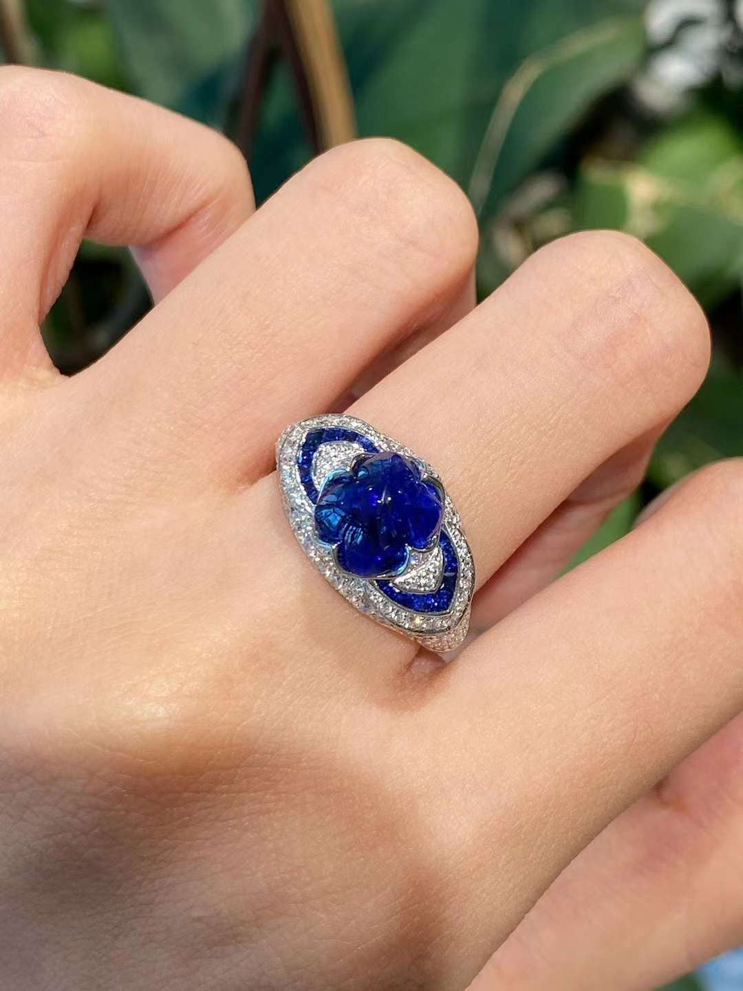 Floral blue gemstone ring worn on hand featuring pavé lab-grown diamonds, marquise halo structure, and high-polish white metal finish