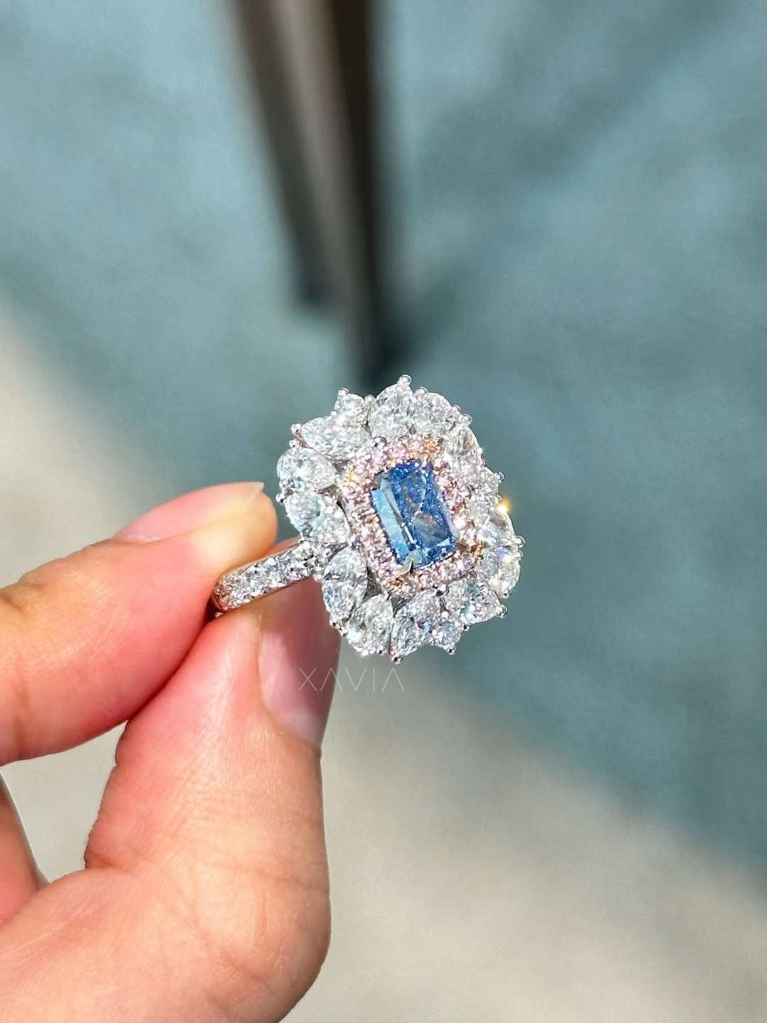 side angled view of royal blue emerald cut ring showing intricate double halo and pavé diamond shank