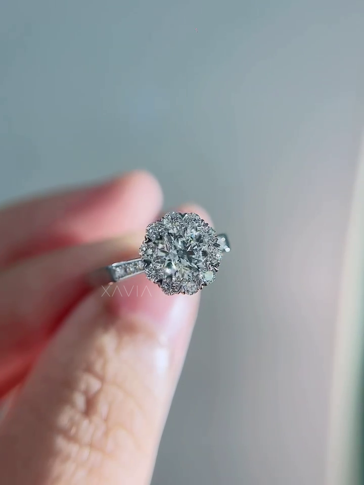Hand-held macro photograph of round lab grown diamond engagement ring with floral halo diamonds and delicate pavé band in white gold