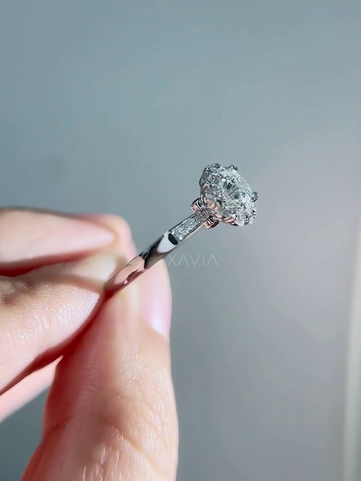 Close macro front view of round diamond engagement ring surrounded by floral halo diamonds with delicate pavé band