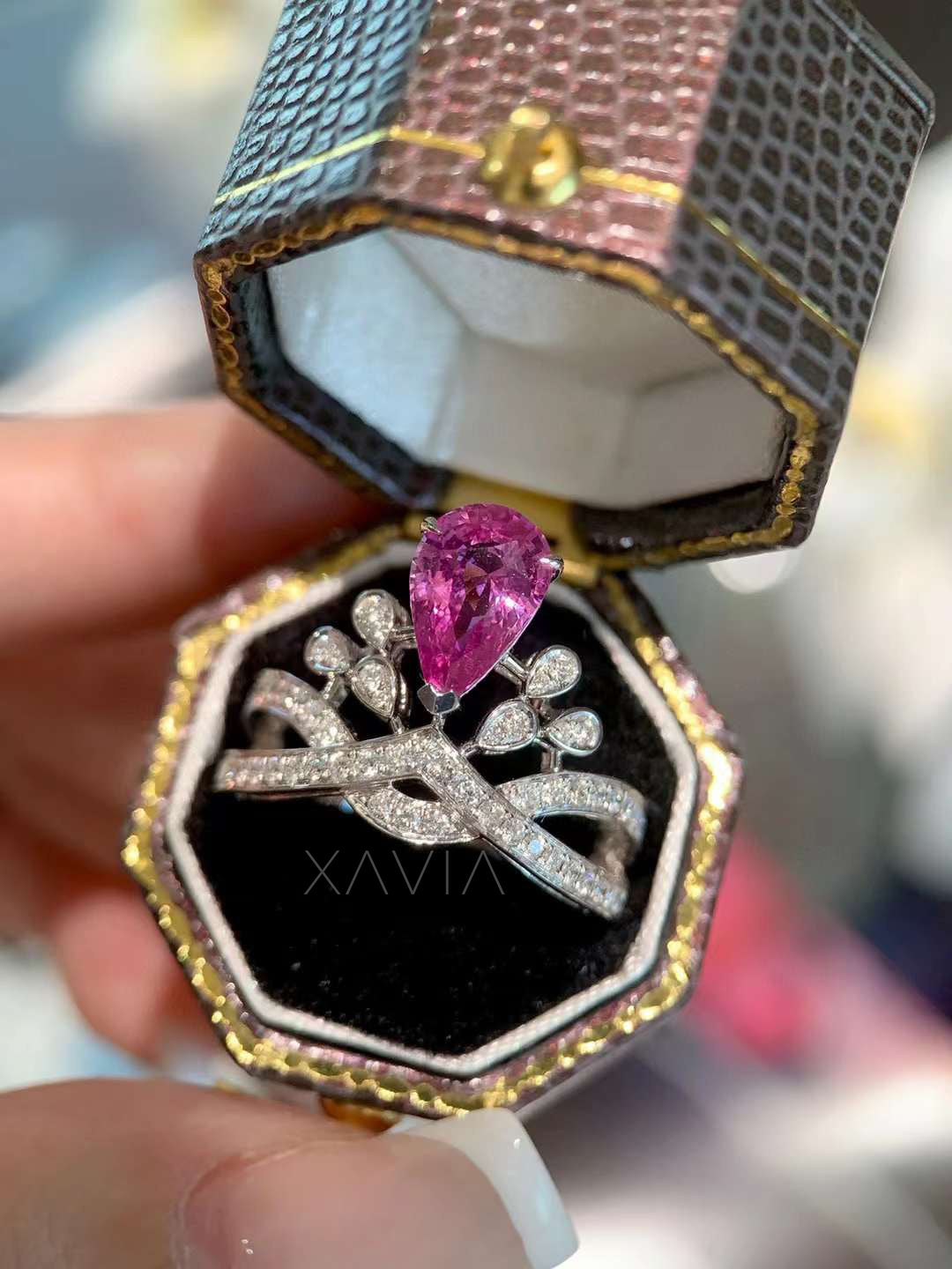 angled view of pear shaped pink diamond ring featuring marquise petal halo and diamond crossover pavé band