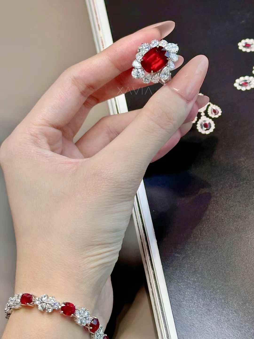 Hand holding a pair of red gemstone earrings with a blurred background