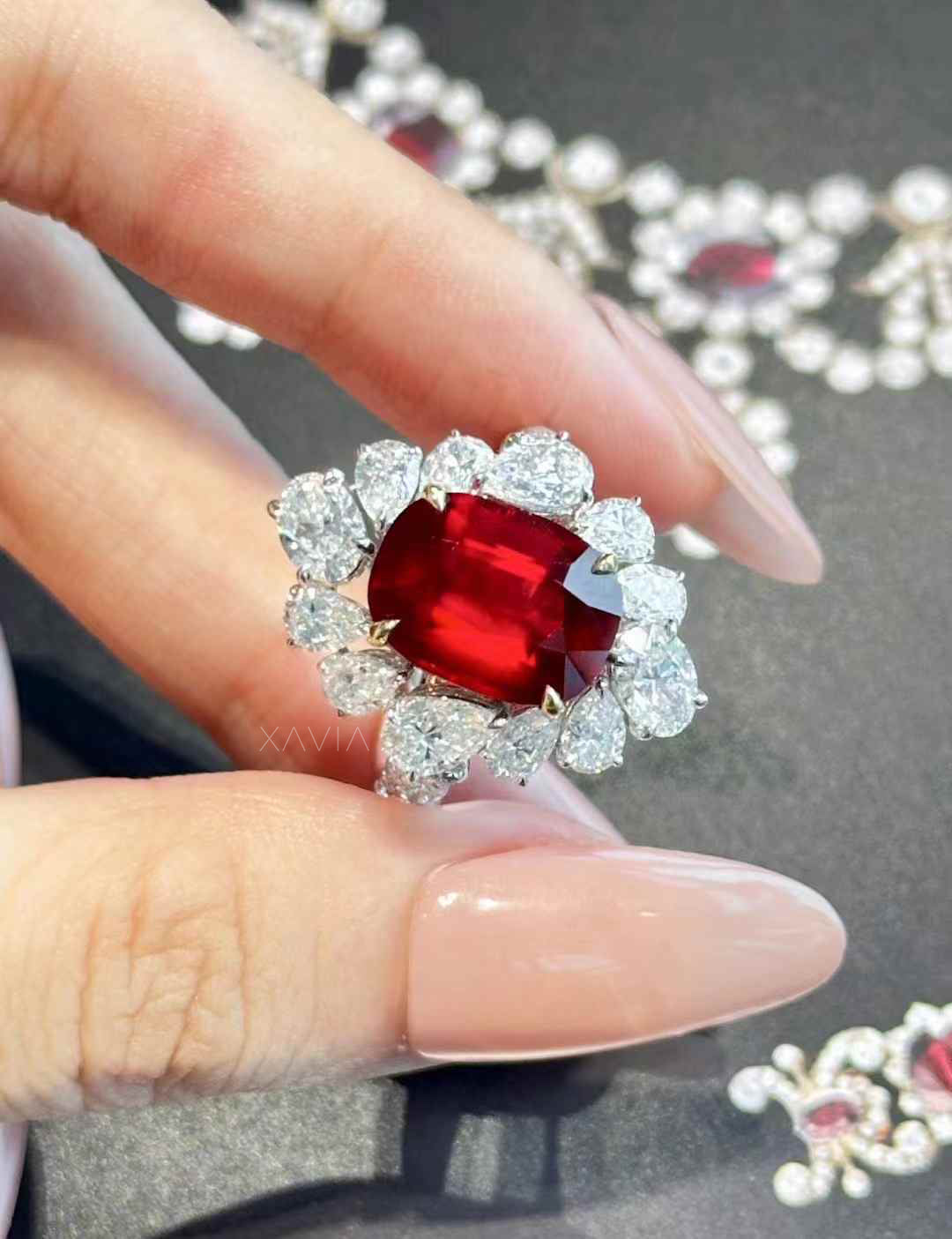 Top view of cushion cut ruby red center stone ring with pear shaped diamond floral halo in high polish white metal