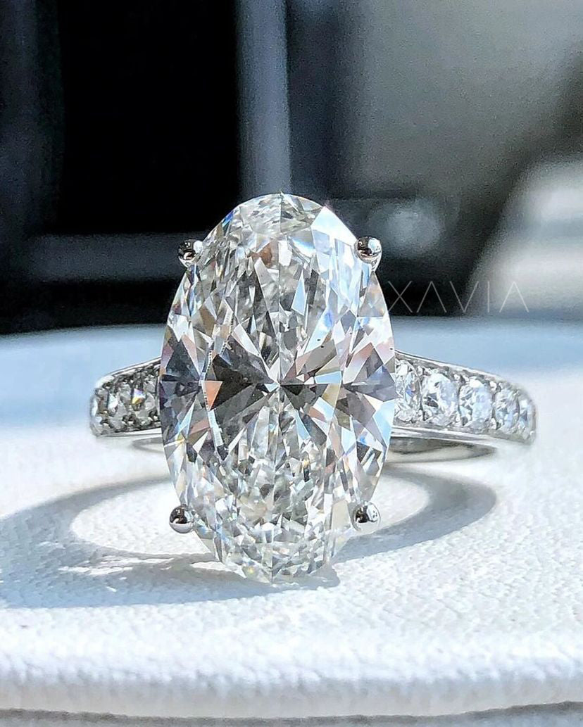 Frontal close-up of large oval cut lab diamond engagement ring with pavé set side stones in platinum band