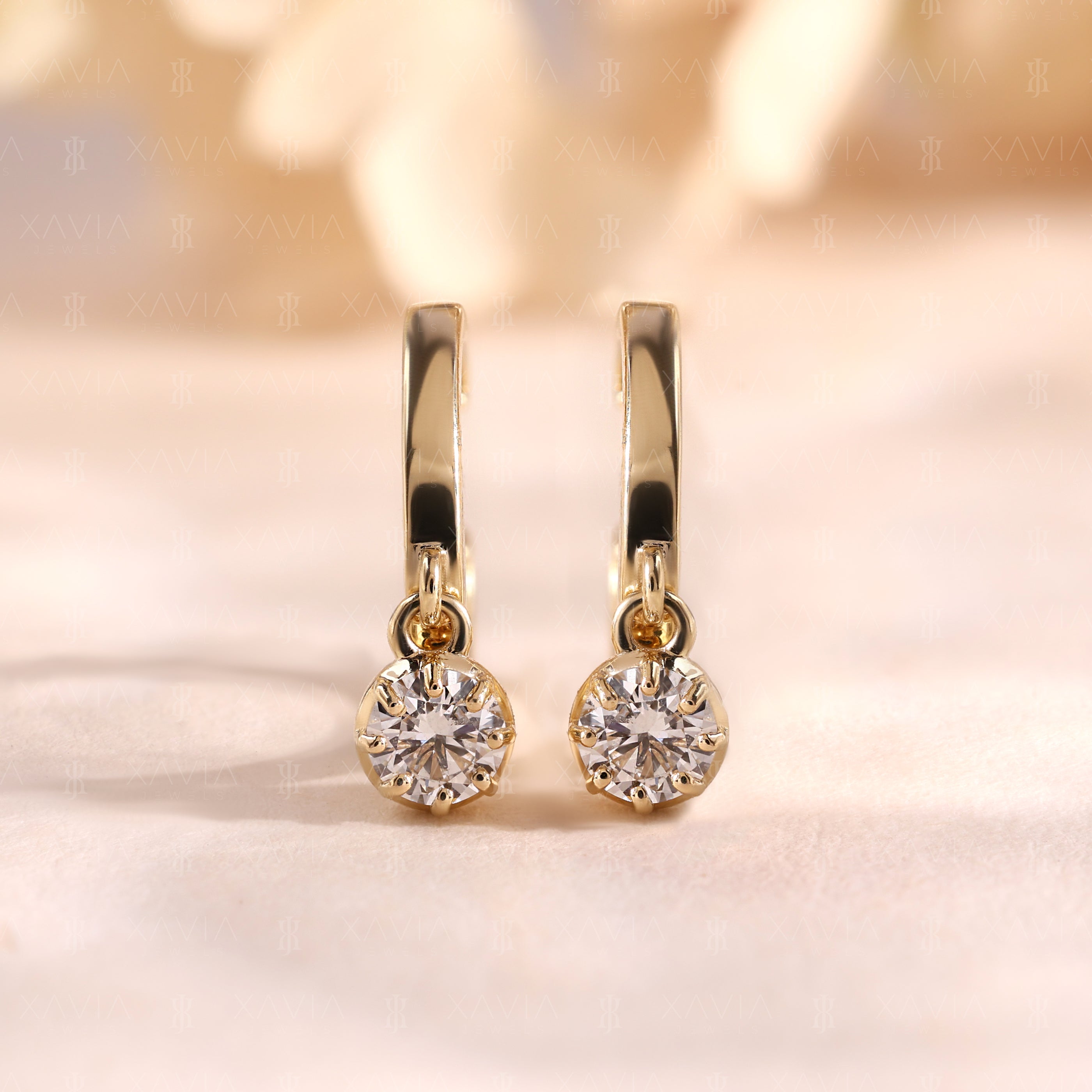 Front-facing view of minimalist yellow gold huggie earrings with round brilliant lab diamond solitaire drops in secure prong settings and polished finish.