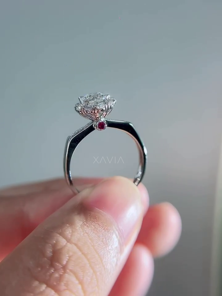 Detailed side angle of diamond halo engagement ring displaying secret ruby gemstone accent set beneath the central diamond crown