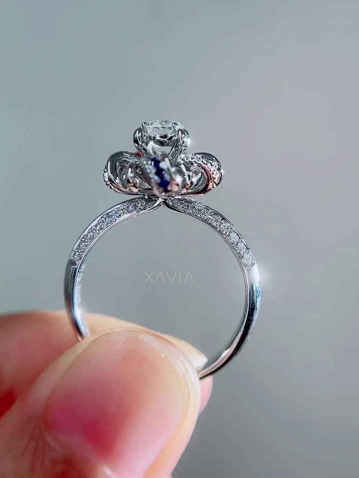 Rear view of halo engagement ring highlighting sculptural petal gallery and blue sapphire accents supporting round center diamond