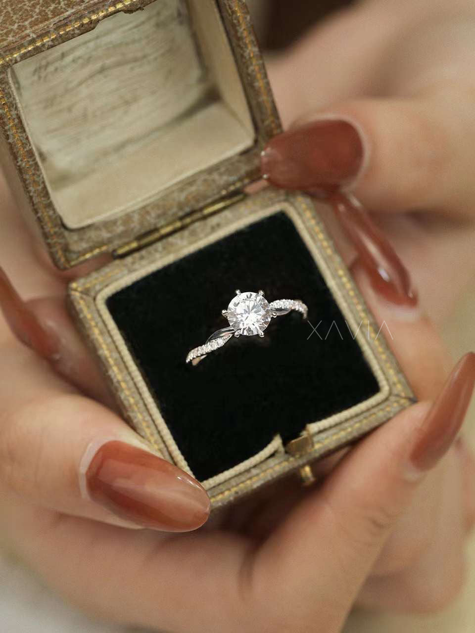 Hand holding solitaire round diamond engagement ring with pavé twisted band in high-polish white gold